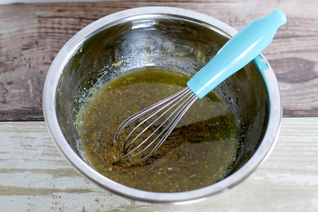 butter, mustard, onion, and poppy seed mixture in a bowl with a whisk