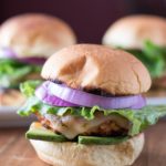 picture of grilled turkey burger sliders from the front with lettuce, red onion, and avocado.