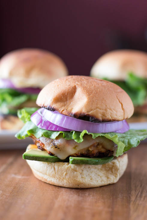 picture of grilled turkey burger sliders from the front with lettuce, red onion, and avocado.