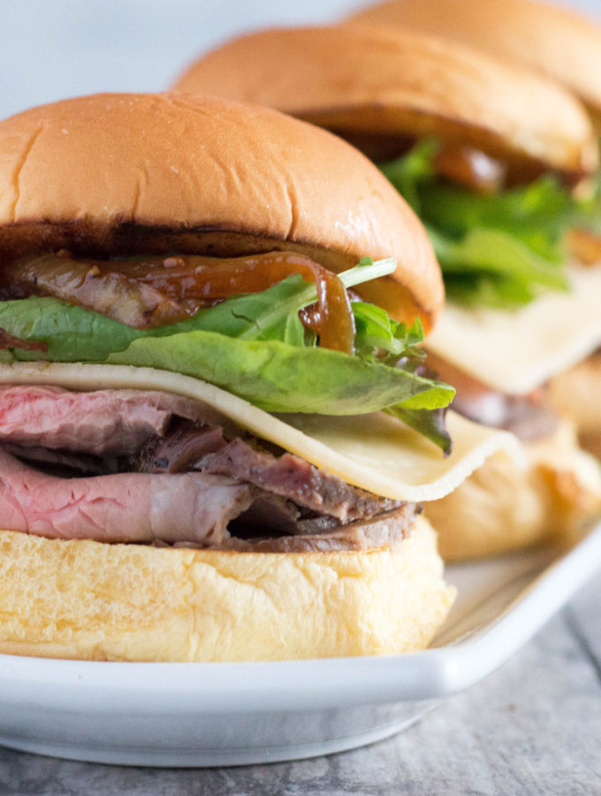 Easy Roast beef sliders topped with gouda cheese, spring mix and caramelized onions