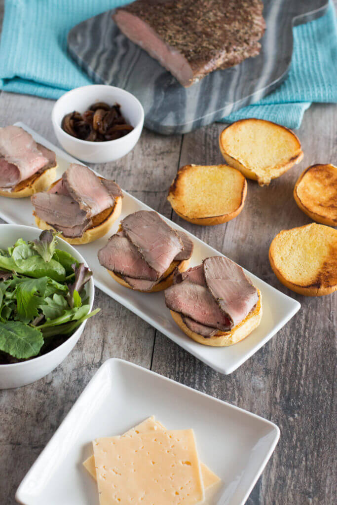 a table space with roast beef, gouda cheese, spring mix and slider buns