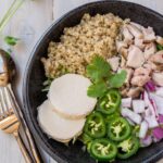 An Instant Pot recipe featuring a bowl with quinoa, chicken, rice, and peppers on a wooden table.