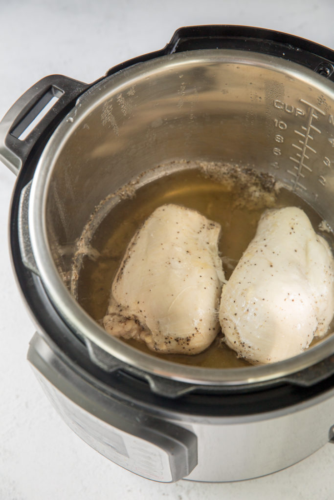 instant pot with cooked chicken breasts in it
