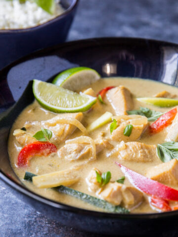 close up image of thai green curry with bell peppers and sliced limes