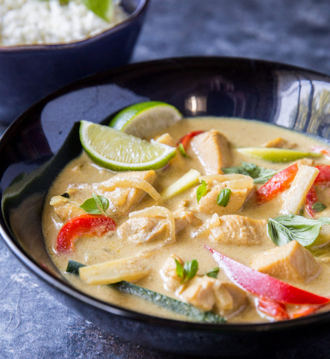 close up image of thai green curry with bell peppers and sliced limes