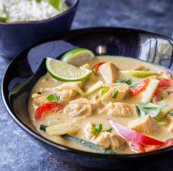 close up image of thai green curry with bell peppers and sliced limes 