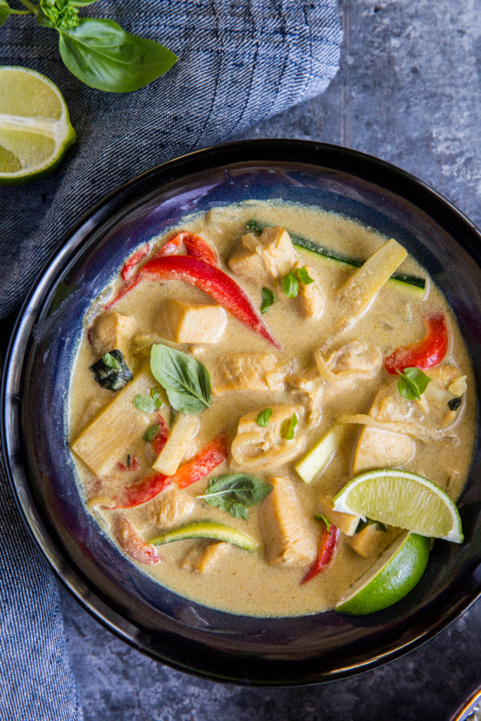 close up image of thai green curry with bell peppers and sliced limes 