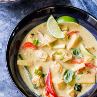 close up image of thai green curry with bell peppers and sliced limes with cauliflower rice