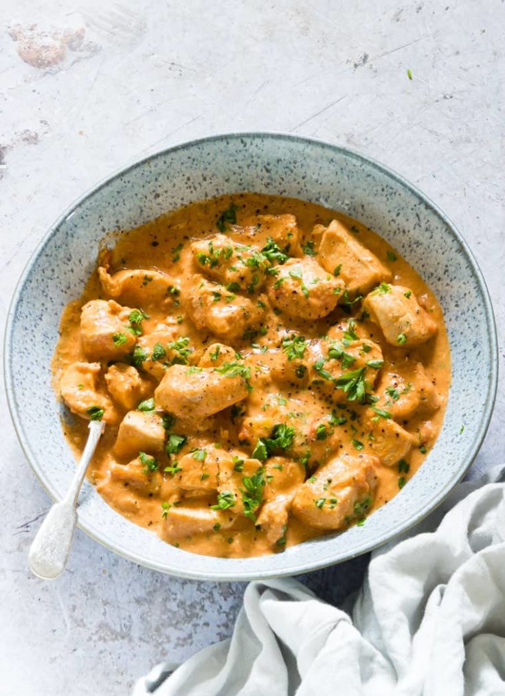 image of nstant Pot African Cinnamon Peanut Butter Chicken in a blue bowl with a silver spoon