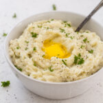 Instant Pot Mashed Cauliflower with a spoon, butter and parsley