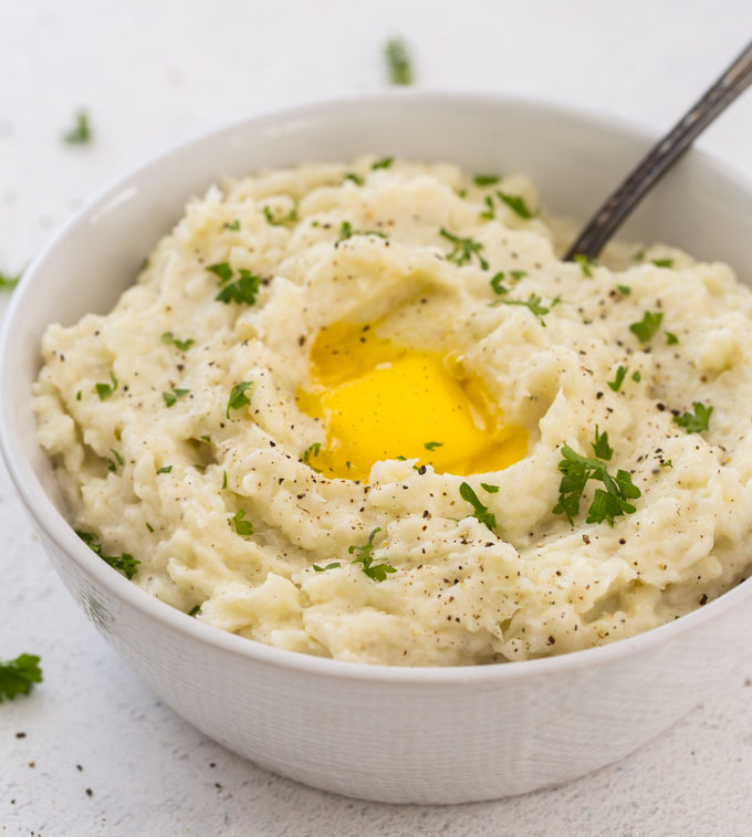 Instant Pot Mashed Cauliflower with a spoon, butter and parsley