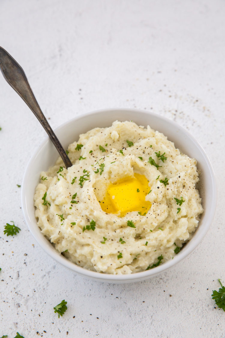 Instant Pot Mashed Cauliflower with a spoon, butter and parsley 