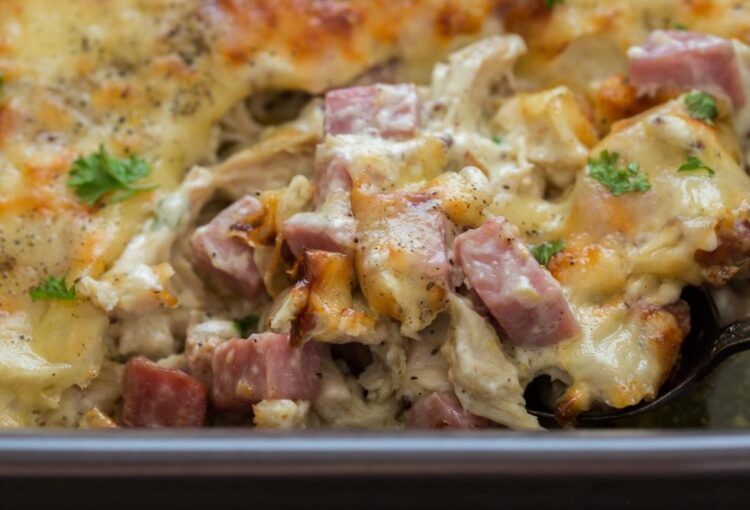 Chicken cordon bleu in a grey baking dish with a silver spoon coming out