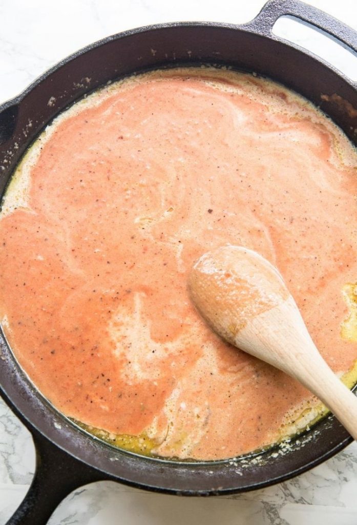red creamy tomato sauce in a pan with a wooden spoon