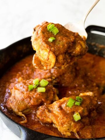 chicken in a pan surrounded and covered in a red sauce