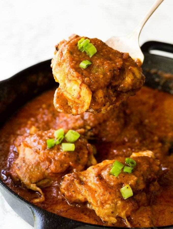 chicken in a pan surrounded and covered in a red sauce