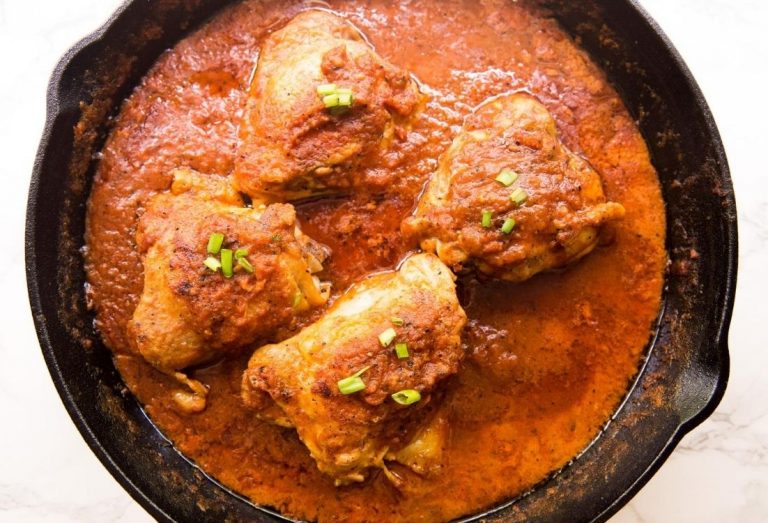 Cast Iron Chicken Thigh in Creamy Tomato Sauce with a spoon in a cast iron skillet.