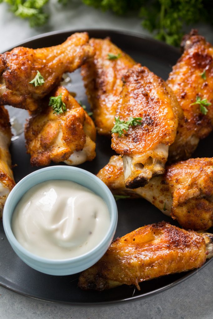 keto chicken wings on a plate with ranch topped with parsley 