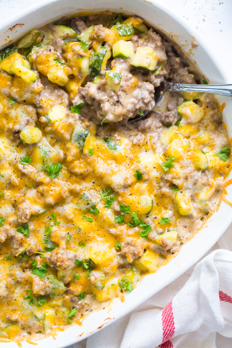 keto ground beef in a white casserole dish with a spoon and topped with parsley 