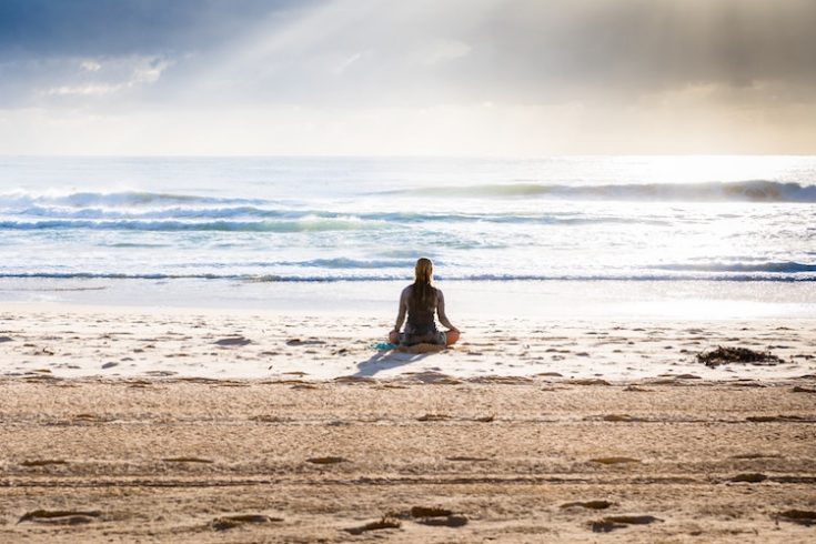 woman meditating at the ocean 