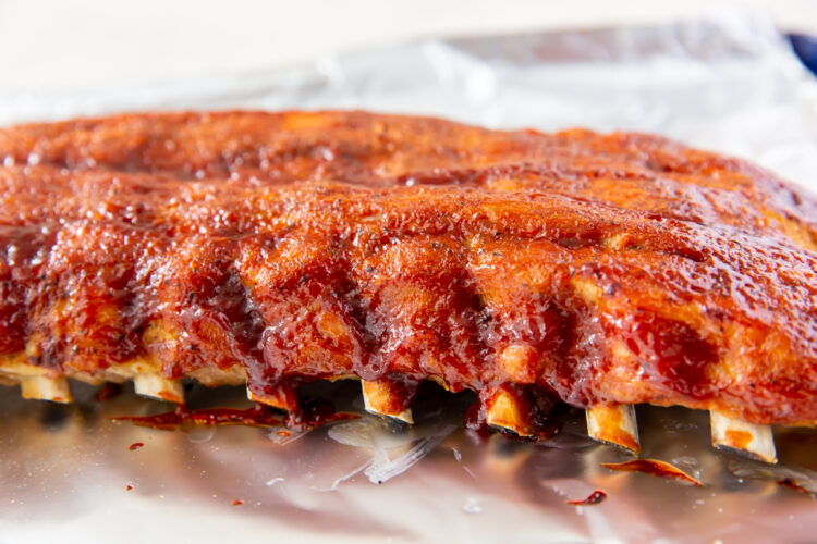 close up image of a rack of baby back ribs on aluminum foil