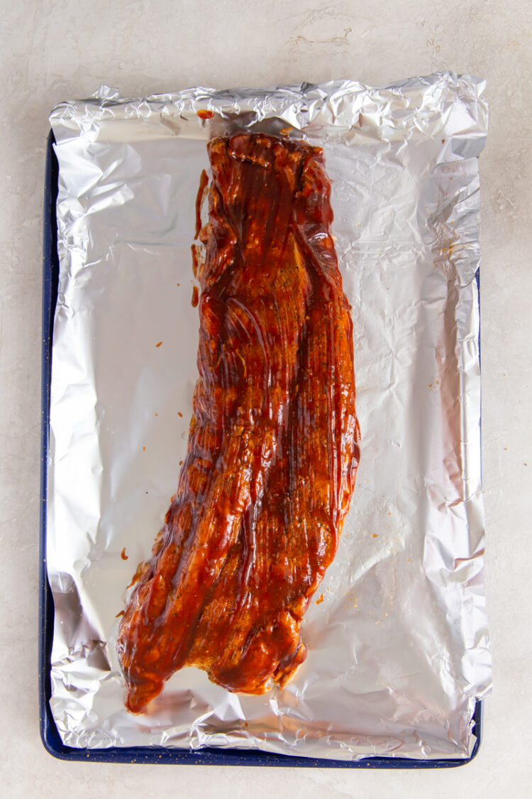 over head image of baby back ribs on a baking sheet with aluminum foil