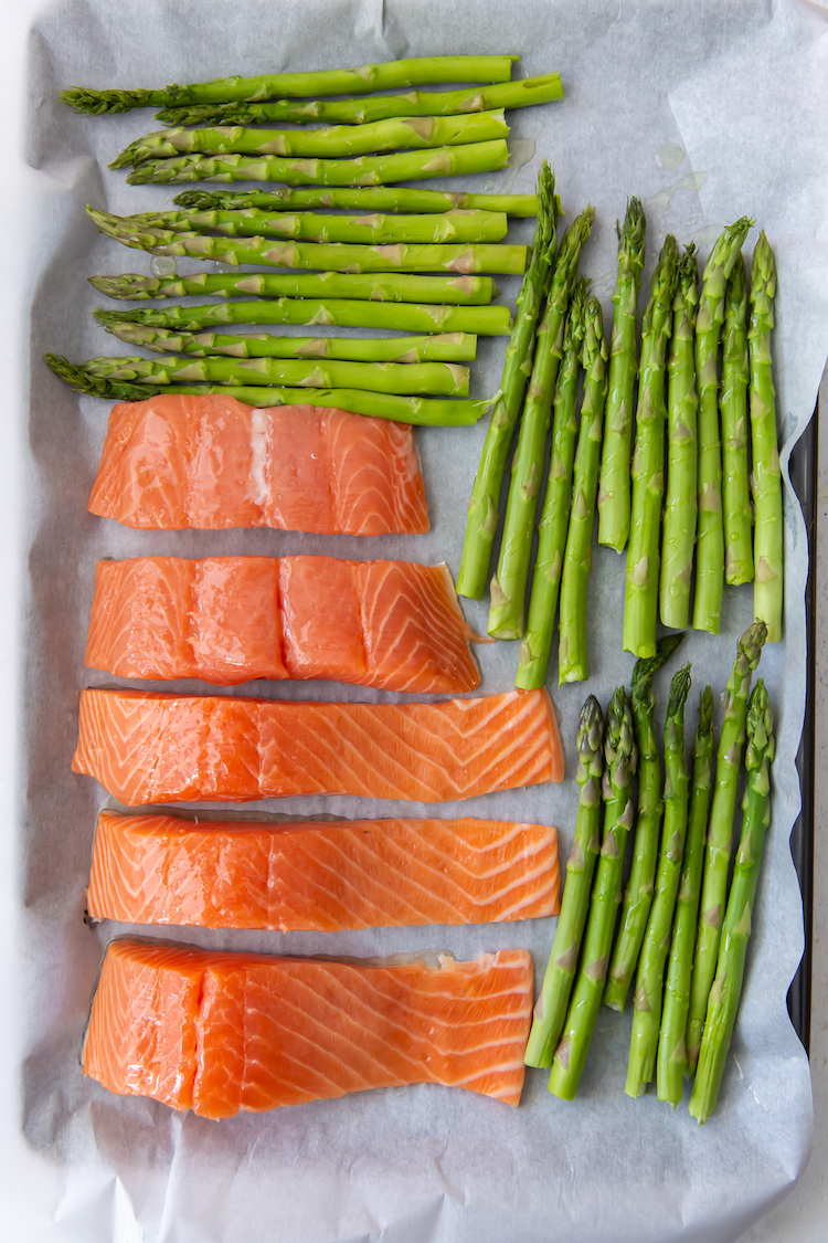 salmon and asparagus on a parchment lined cookie sheet