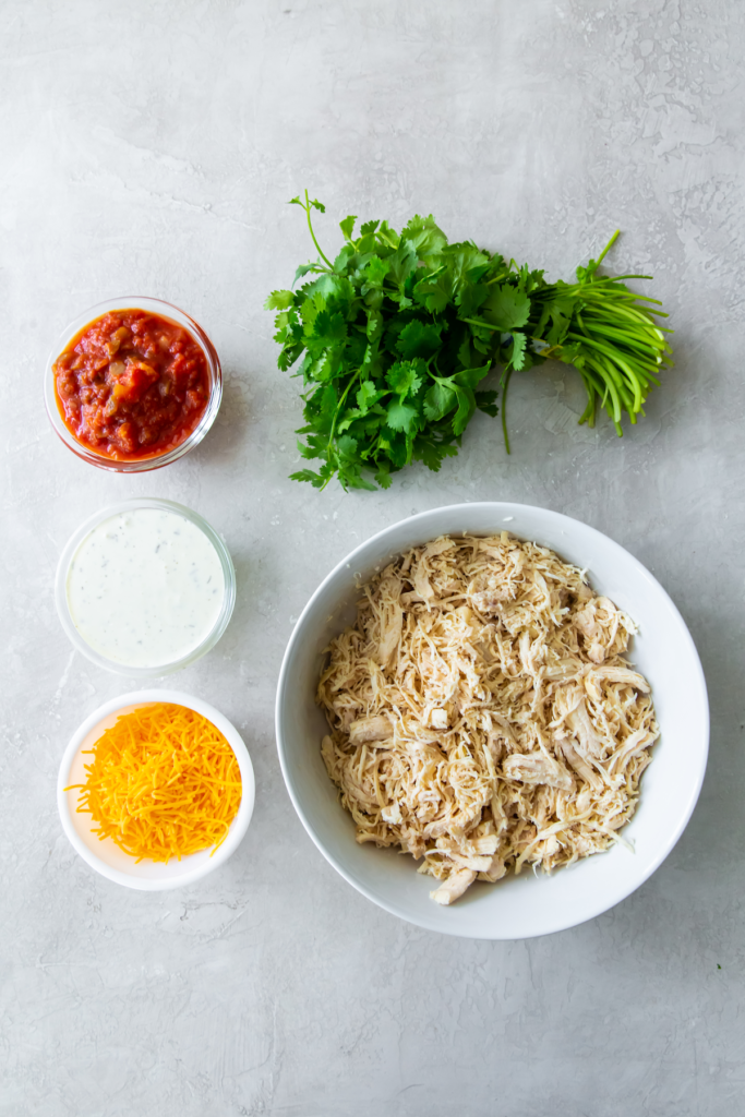 shredded chicken breast in a bowl, shredded cheese, salsa, ranch, cilantro