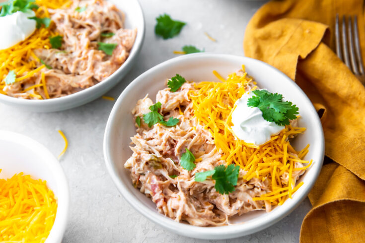 creamy Instant Pot salsa chicken in a bowl topped with cheese, sour cream and cilantro