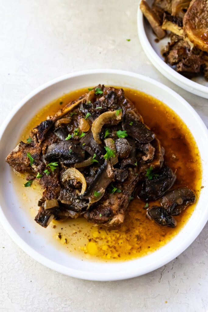 pork chops with mushrooms and onions on a white plate