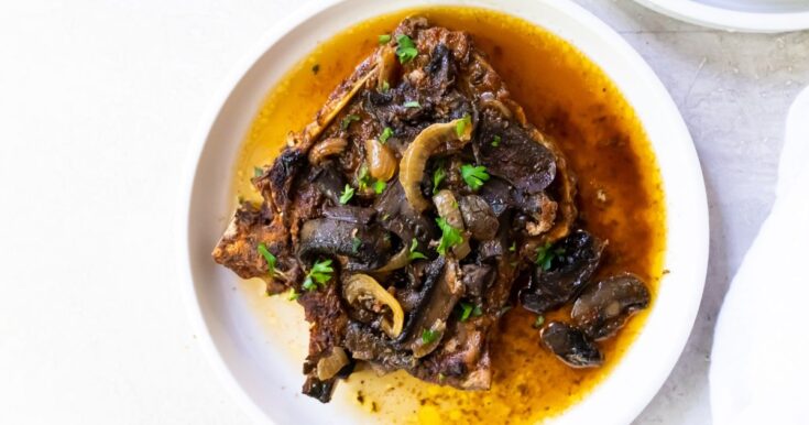 pork chops with mushrooms and onions on a white plate