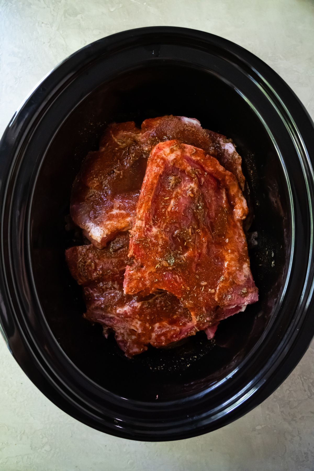 spices and broth poured over pork chops in a crockpot