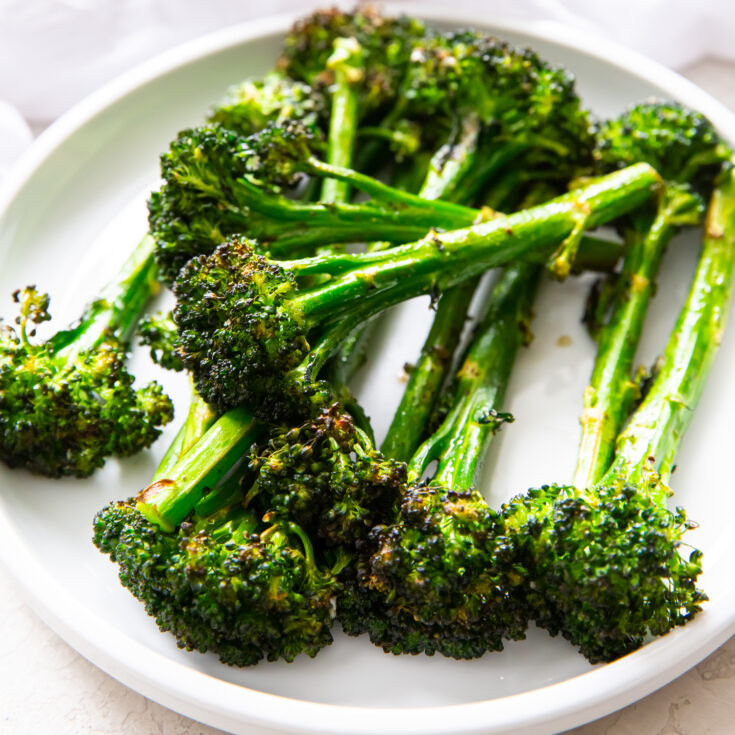 air fryer broccolini on a white plate with a white napkin