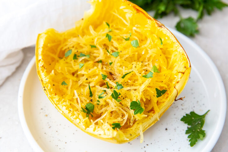 air fryer cooked spaghetti squash on a white plate with parsley and white napkin