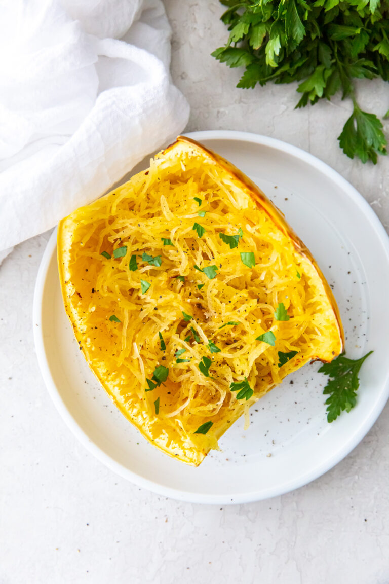 Air Fryer Spaghetti Squash on a white plate with parsley, salt, and pepper.