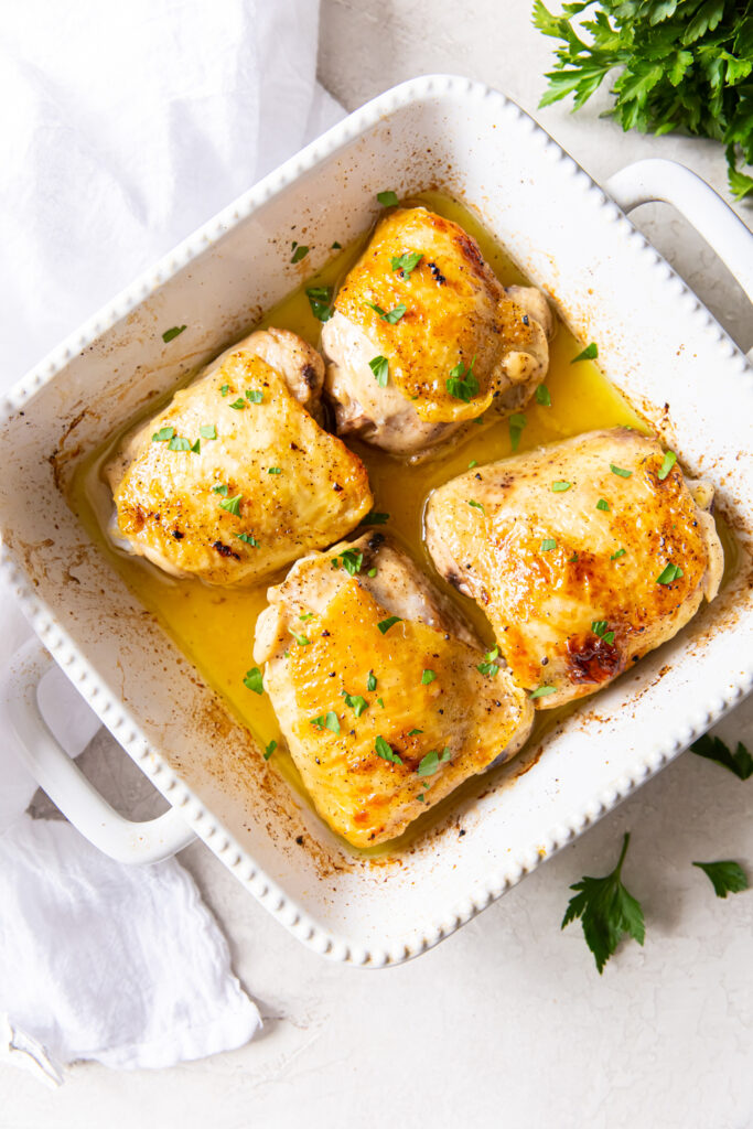 broiled chicken thighs in a square white baking dish