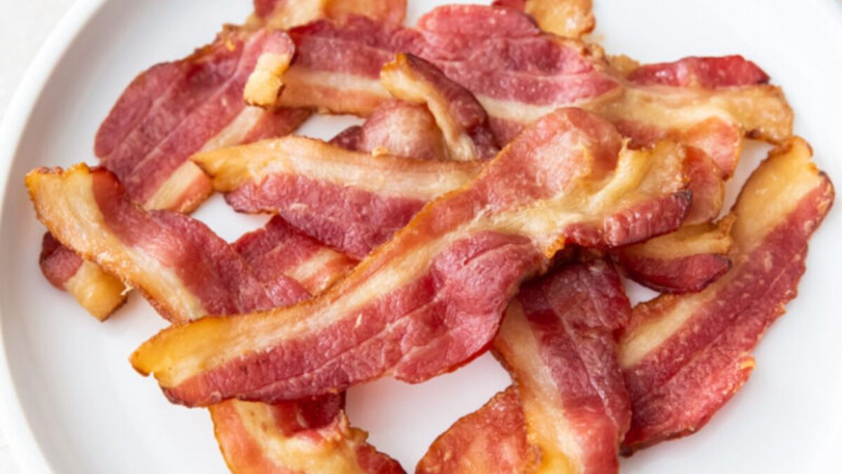 air fryer crispy bacon piled high on a white plate.