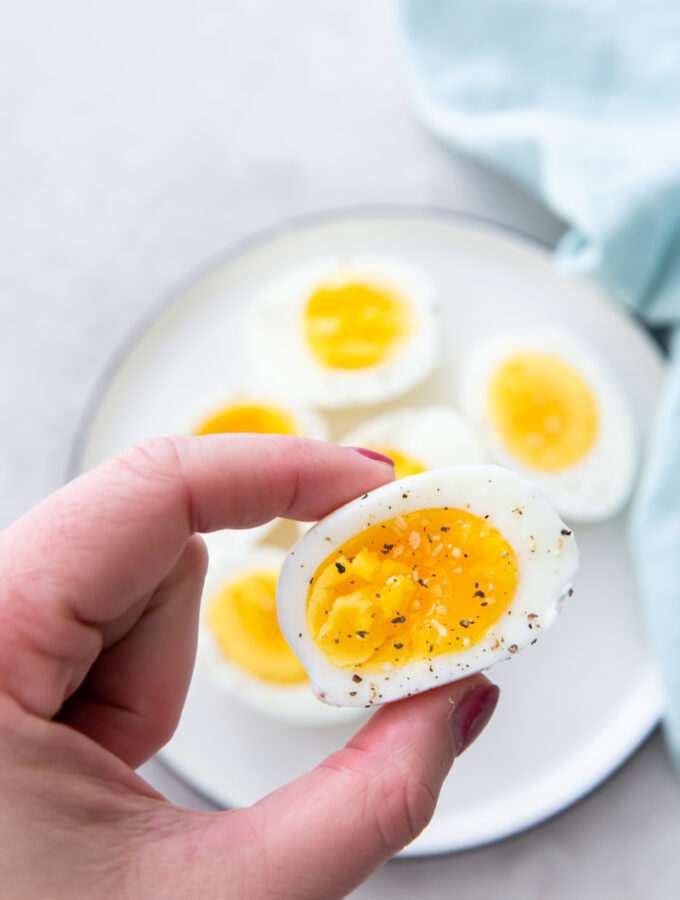 holding a hard boiled egg with salt and pepper