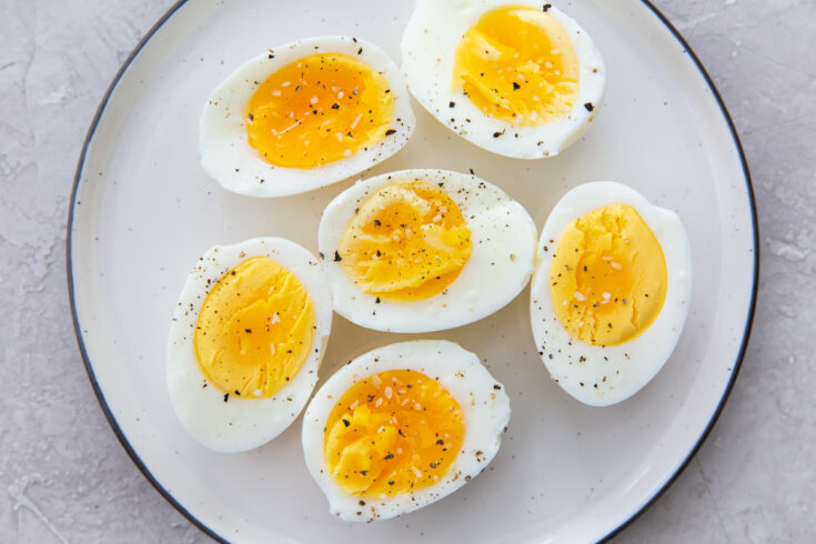 air fryer hard boiled eggs on a white plate with salt and pepper