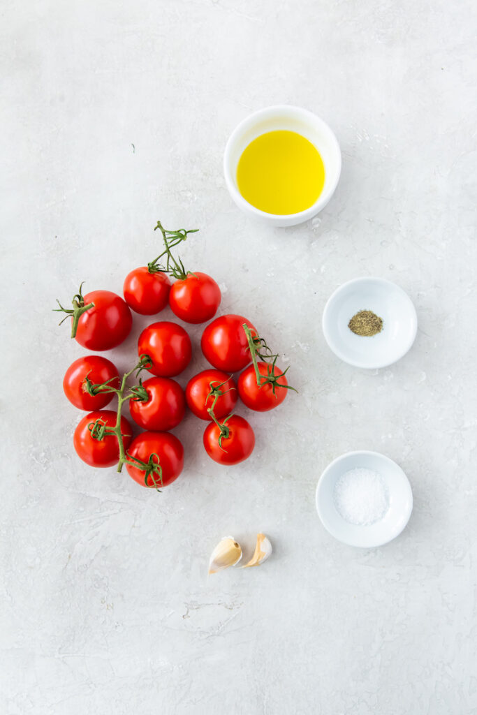 tomatoes, olive oil, pepper, salt and garlic on a grey surface