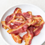 a pile of bacon on a white plate