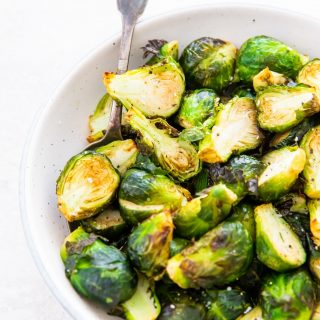 Brussel sprouts in a white bowl with fork inside the bowl to the left