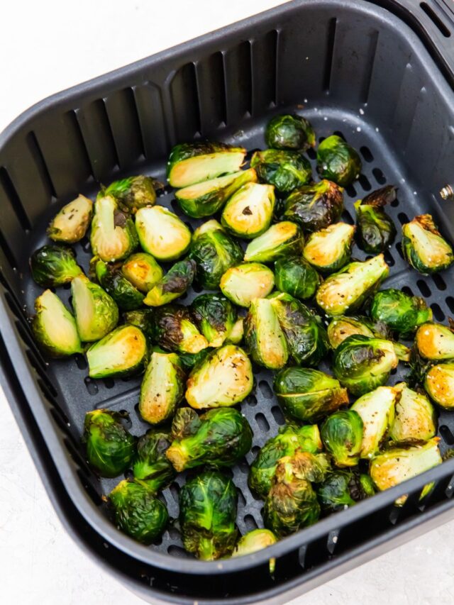 cooked halved brussel sprouts in an air fryer basket.