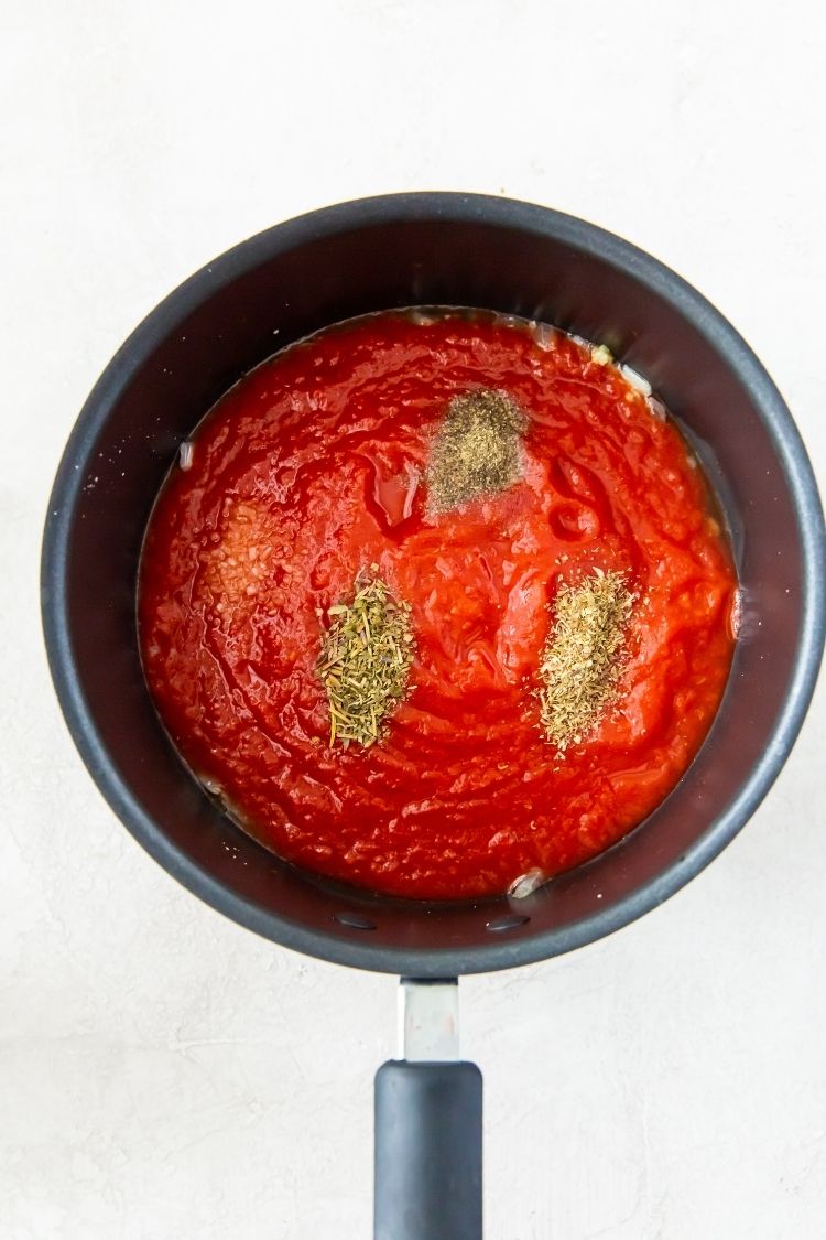 crushed tomatoes in a saucepan with spices on top