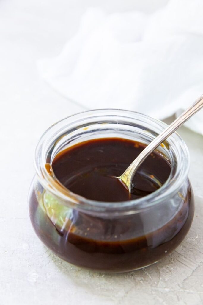 honey paleo teriyaki in a glass container with a spoon on a light background