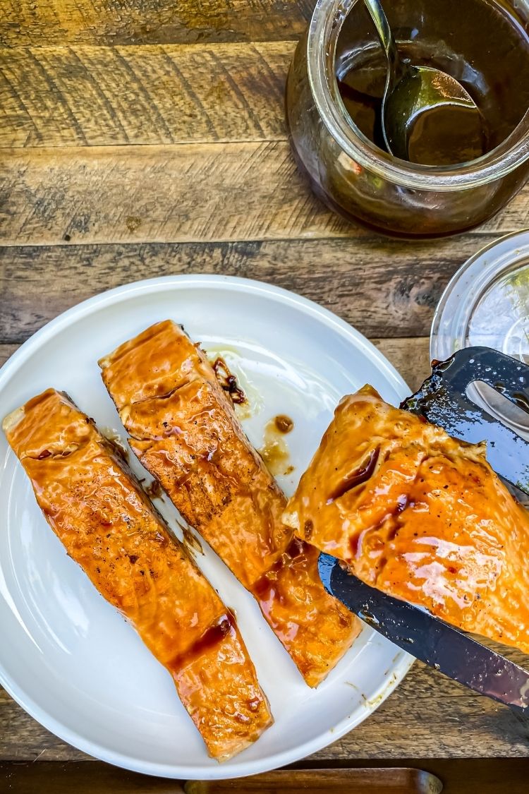 Teriyaki salmon on a white plate and spatula