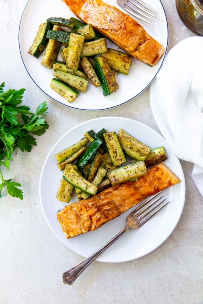 grilled teriyaki salmon with grilled zucchini and a fork on a white plate