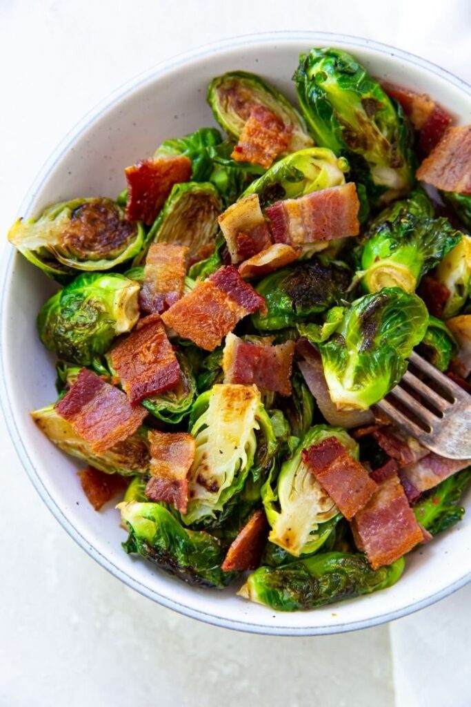 Brussel sprouts with bacon in a white bowl with a fork