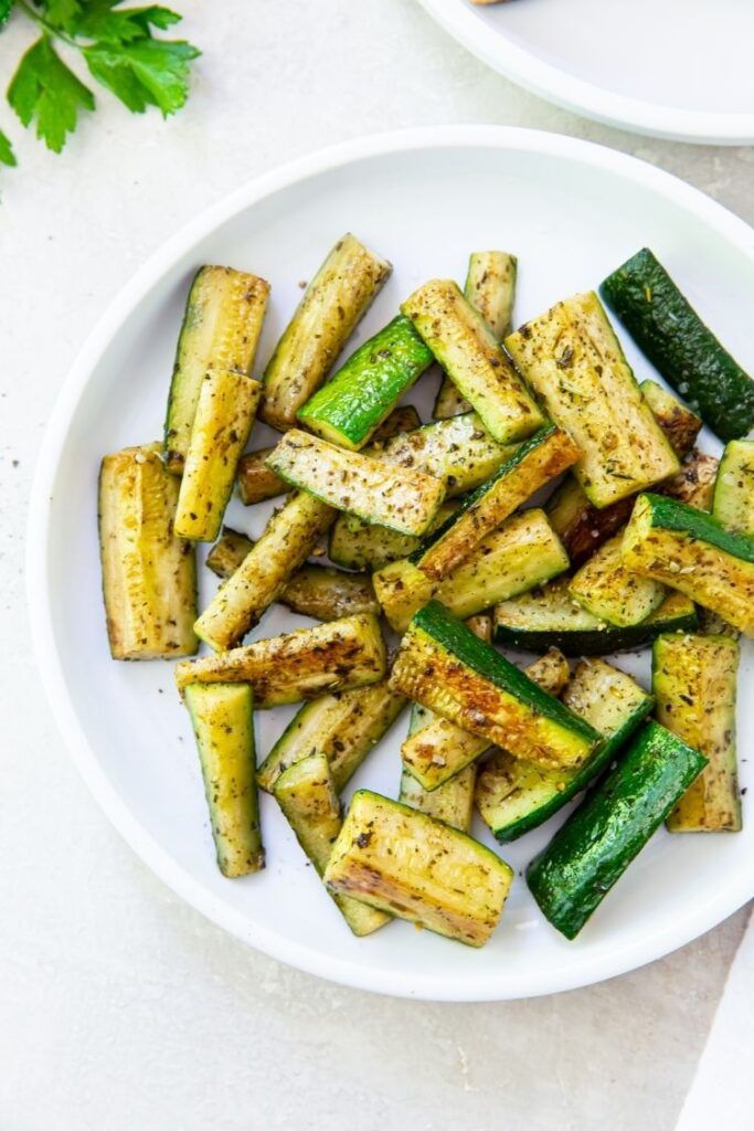 Blackstone Zucchini on a white plate on a white background with parsley