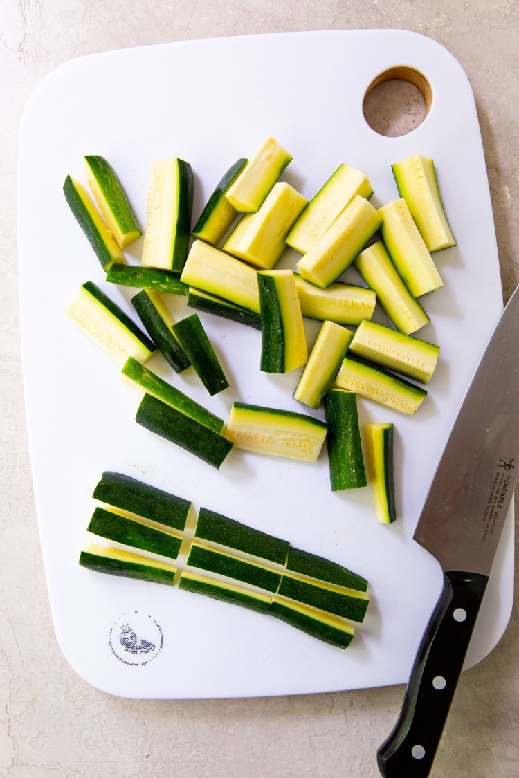 zucchini cut on a white cutting board with a knife